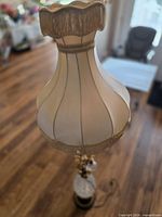 Full view showing fabric shade with fringe and lamp body