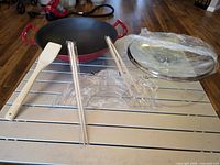 Wok, glass lid, wooden spatula, wire rack and chopsticks displayed on table