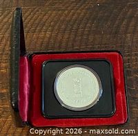 Coin in capsule inside red-lined black presentation case