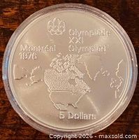Reverse of the 1973 Canada $5 Montreal Olympics coin showing world map design and denomination
