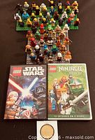 Group of LEGO minifigures on baseplates, two LEGO DVDs, Legoland token visible