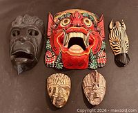Group shot of all five wooden masks displayed on flat surface