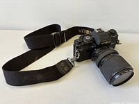 Front angled view showing Minolta X-700 camera body, attached zoom lens, and fabric strap