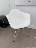 Front angled view of white molded armchair showing right arm, bucket seat, and chrome Eiffel legs