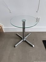 Full view of round glass side table showing glass top and chrome base