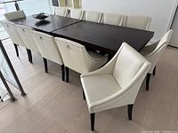 Dining table surrounded by twelve white faux leather chairs, showing overall style and colour