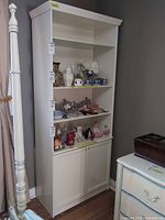 Front view showing entire white bookcase with three shelves and lower cabinet doors