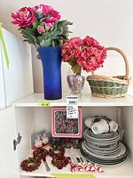 Overall lot: vases with faux florals, wicker basket, dinnerware and accessories in cabinet