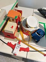 All items grouped: playset, drum, tambourine, drumsticks, police car, bow, table