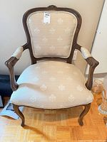 Front view of carved wood French Provincial armchair with beige damask upholstery