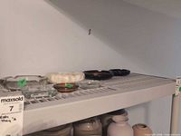 Six ashtrays on shelf, various shapes and colors