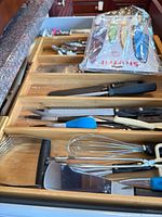 Drawer view showing knives, honing rod, packaged Starfrit knife set, grater, whisk, pastry blender and other utensils