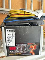 MotoMaster Eliminator charger in its box with carry bag and clamp leads visible