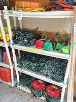Front view of white plastic four-shelf unit holding assorted garage items (contents not included)