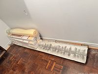 Stacked boxes of Satin Finish engineered hardwood planks with roll of underlayment and opened box