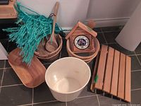 All sauna accessories together: wooden bucket, ladle, thermometer in hut frame, slatted footrest, white plastic basin, teal whisk, wooden tray