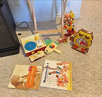Entire lot showing record player, Rubik’s Cube, books, movie viewer, clock toy and small figures grouped on floor