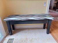 Full frontal view of bench showing black wood frame and zebra upholstery