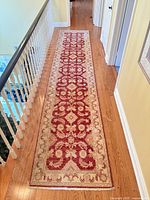 Top view of full length wool red ivory oriental runner rug on hardwood floor