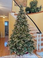 Full view of assembled 9 ft pre-lit flocked tree with lights on