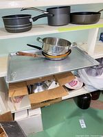 Shelf with multiple pots and pans, baking sheet, boxed jars visible