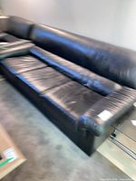 Front angled view of entire sofa showing three seat cushions and leather condition