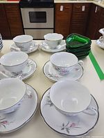 Five tea cup and saucer sets with stacked green bowls