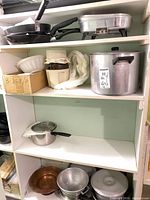 Shelved cookware including frying pans, electric skillet, stock pot, grinder, molds