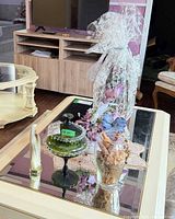 All four items displayed on coffee table: green compote, potpourri vase, Virgin Mary figurine, wrapped floral topiary