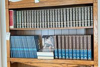 Shelf view showing three encyclopedia sets: top row Funk & Wagnalls, lower left Illustrated World of Science, lower right Britannica volumes