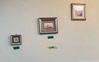 Three framed prints on wall, showing two small and one medium gold-frame pieces