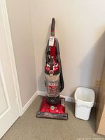 Full view of Hoover UH72600 upright vacuum standing in corner, hose wrapped around handle