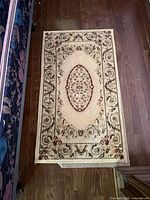 Full view of first beige floral medallion rug on hardwood floor