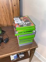 Stack of ten green Xbox game cases; top case shows James Bond 007 title