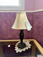 Table lamp on glass-top table showing full base and shade