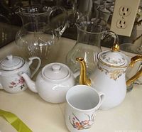 Group shot of all items: Ginori coffee pot, two teapots, mug, two glass pitchers