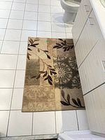 Rectangular beige-tan floral area rug on tiled bathroom floor