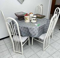 Dining table surrounded by six white metal chairs with gray seats