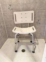 Front view of shower chair showing full frame, seat, backrest and rubber feet