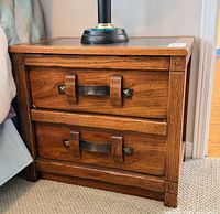 Front view showing two drawers with leather strap pulls and metal accents