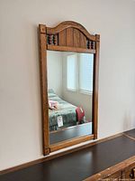 Full view of wall-mounted solid oak mirror showing arched top and surrounding furniture for scale