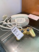 Front view of gold Sony PS3 controller and clear-base Telean telephone showing overall appearance