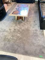 Full view of grey synthetic rug under coffee table and between sofas