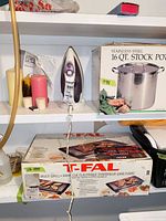 Shelf with T-fal steam iron, assorted pillar candles visible beside iron