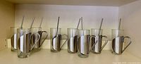 Full set of eight glass mugs in stainless holders with straws