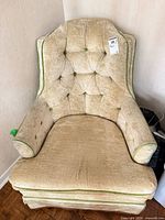 Front view showing beige crushed velvet upholstery, green piping, tufted buttons