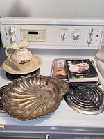Overview of lot on stove showing ceramic pitcher, basin, metal tray, two boxed serving items