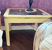 Overall view of cream wood end table with glass inset top against purple wall