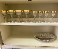 Shelf with eight goblets, six cordials, and nested metal trays below