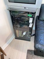 Cabinet with television on top and audio components inside, glass door absent